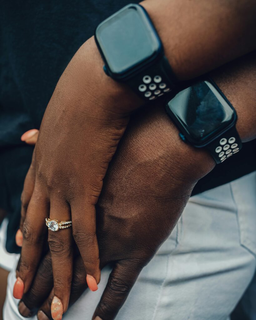 Two hands with smartwatches, one adorned with a diamond ring, symbolizing modern connection.